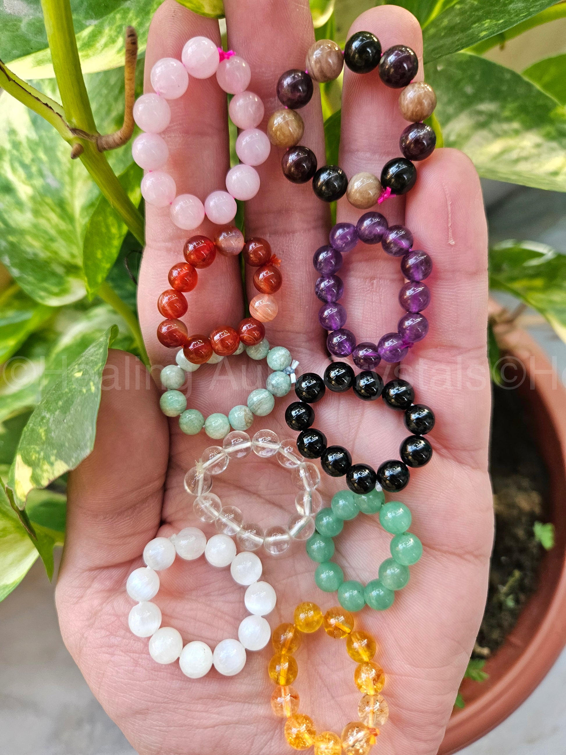 Hand holding a collection of colorful beaded bracelets with a natural background