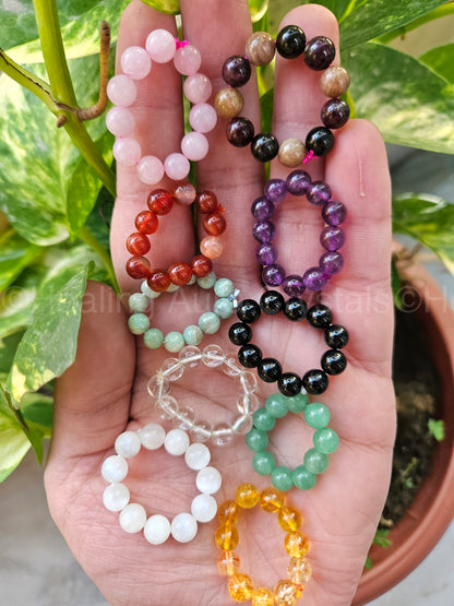 Hand holding a collection of colorful beaded bracelets with a natural background