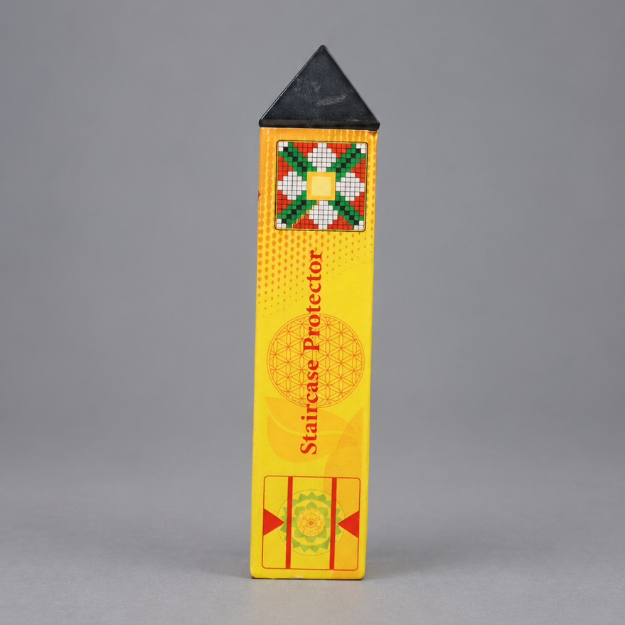 A yellow rectangular staircase protector with a black pointed top, standing upright against a neutral gray background. The box features a colorful geometric pattern near the top and red text reading 'Staircase Protector'.