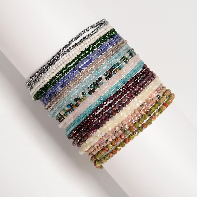 Stack of multicolored beaded bracelets on a white surface