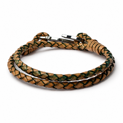 A braided leather bracelet in natural tan with dark green accents, featuring a silver-toned metal clasp, shown on a plain white background.