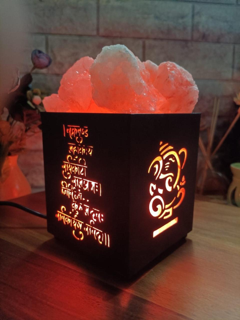 Decorative lamp with Ganesha design and text on a wooden surface.