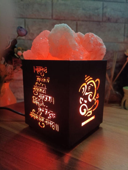 Decorative lamp with Ganesha design and text on a wooden surface.